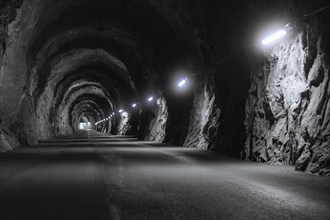 A long, gloomy tunnel with illuminated rock faces and a tarmac path, Zillertal, Austria, Germany,