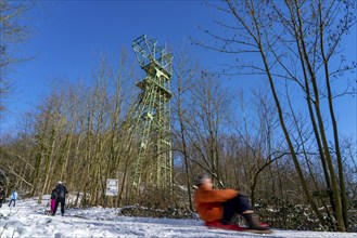 Winter in the Ruhr area, toboggan run on a forest path at Lake Baldeney, headframe of the former