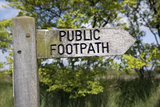 Wooden public footpath sign pointing direction, Suffolk, England, UK