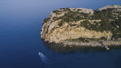 Drone shot, A rocky seashore with a small boat, calm water and a cloudless sky, Anthony Quinn Bay,