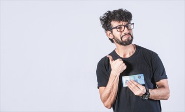 Man holding a banknote with thumb up isolated. Person holding bill with gesture aproved isolated