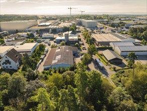 Industrial area with various buildings and a crane in the background, trees along the streets,