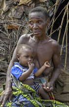 Pygmy woman of the Baka or BaAka people with her child in front of her hut, Bayanga, Sangha-Mbaéré