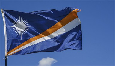 The flag of the Marshall Islands, Pacific Islands, flutters in the wind, isolated against a blue