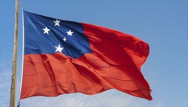 The flag of Samoa, fluttering in the wind, isolated against a blue sky