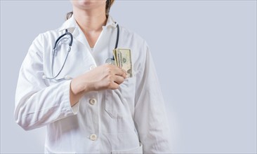 Unrecognizable doctor putting bribe money in pocket isolated. Dishonest female doctor putting money