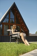 Young woman sunbathing on the lawn of a modern tiny house