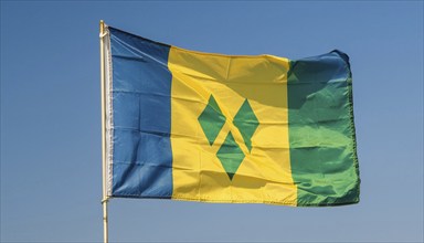 The flag of the Grenadines flutters in the wind, isolated against a blue sky