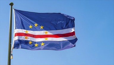 The flag of Cape Verde flutters in the wind, isolated against a blue sky