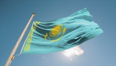 The flag of Kazakhstan flutters in the wind, isolated against a blue sky