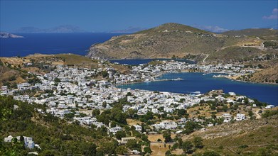 Picturesque coastal town with white houses and mountains in the background, surrounded by blue sea