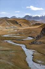 River Kol Suu winds through a mountain valley with hills of yellow grass, Naryn Province,