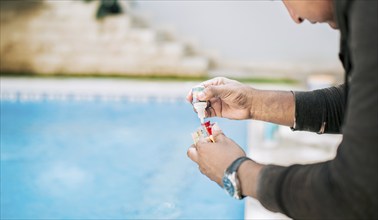 Man using tester kit to measure chlorine and ph in swimming pools. Person testing the PH of the