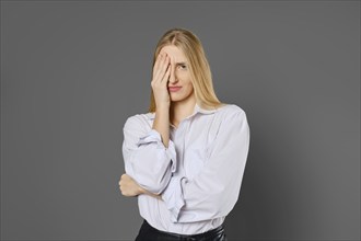 Portrait of a tired and frown young woman covering one eye with her palm