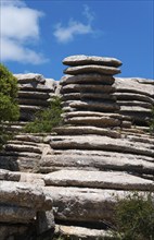 Round rock formations under a blue sky with scattered clouds and green vegetation, Karst Mountains,