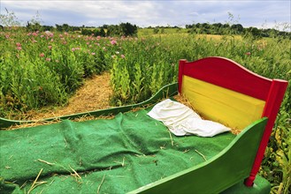 Colourful wooden bed outdoors, mattress made of straw, original hiking trail in the poppy field,