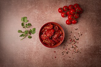 Dried tomatoes, in a bowl, top view, on a brown background