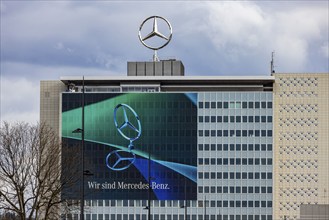 Mercedes star in front of dark clouds, office building at the headquarters of Mercedes-Benz Group