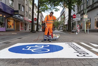 Application of road markings for a cycle lane, Rüttenscheider Straße in Essen, in the shopping and