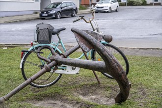 Bicycle, ladies' bicycle, well secured with a bicycle lock to an iron ship's anchor, in