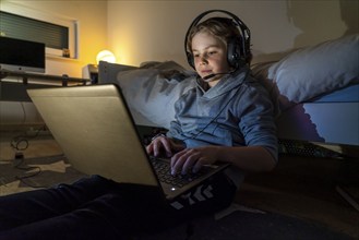 Boy, at home on the computer, laptop, in the children's room, playing a game, chatting with other