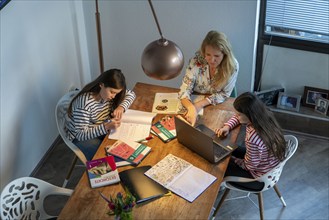 Homeschooling, during the lockdown in January 2021, mother helps her two daughters, at home,