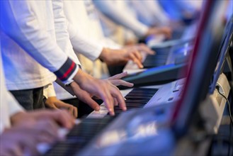 Young people, children play on many keyboards, simultaneously, electronic clarinet, at a concert