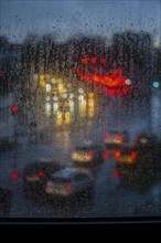 Rainy weather, road traffic, raindrops on a window pane, behind, blurred, lights of vehicles on a