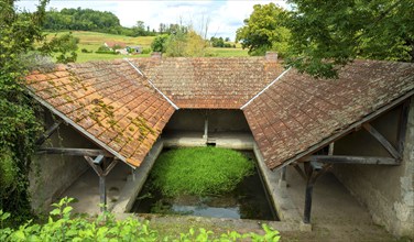 Washhouse in Montaigu-le-Blin village features a grassy basin, Allier. Auvergne-Rhone-Alpes,