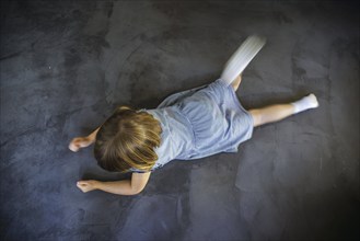 Symbol photo on the subject of tantrums (posed scene) . A little girl is lying on the floor,