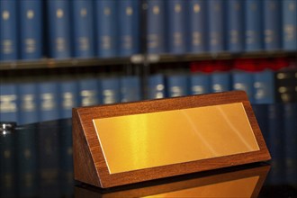 Brass sign with space for text in front of a large bookshelf