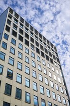 A modern skyscraper with many glass windows stands in front of a cloudy sky, Bergen, Vestland,