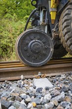 Large wheel on railway tracks with ballast and green background, track construction, Hermann