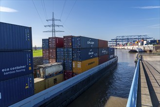 Container cargo ship enters the port basin of the Logport, gantry cranes in the Container Handling