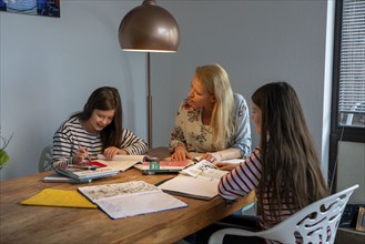 Homeschooling, during the lockdown in January 2021, mother helps her two daughters, at home,