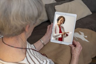 Symbolic image of telemedicine, patient speaking to a doctor in a video conference from home