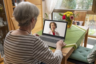 Symbolic image of telemedicine, patient speaking to a doctor in a video conference from home