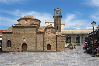 Stone church with bell tower, tourists nearby on a street, Byzantine church, Church of the