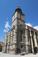 Gothic church with tower under clear blue sky, large clock visible, Black Church, Old Town, Brasov,