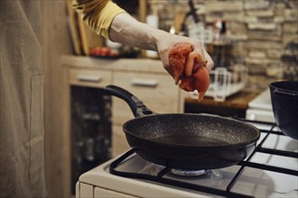 Unrecognizable man moving chopped chicken fillet on a hot frying pan