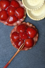 Topped strawberry tartlets with fork and empty tartlet bases