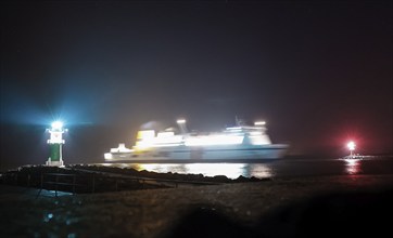 On its journey to Rostock harbour, a ferry passes a lighthouse, Warnemünde, 09.02.2023