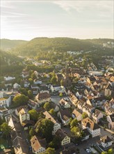 Close-up of a village with a church surrounded by hills and trees in the warm light of sunset,