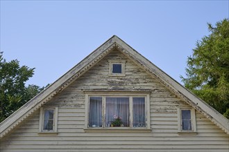 Rustic wooden house with several windows, curtains and flowers against a clear sky, Sandnes, Fylke