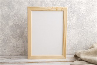 White wooden frame mockup with linen textile on gray concrete background. Blank, vertical