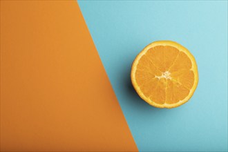 Ripe cut orange on orange and blue pastel background. Top view, flat lay, copy space. Tropical,