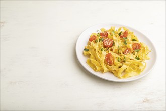 Reginelle semolina pasta with tomato, eggs, sesame and microgreen sprouts on a white wooden