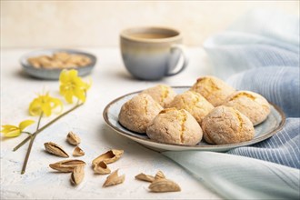 Almond cookies and a cup of coffee on a white concrete background and blue linen textile. Side