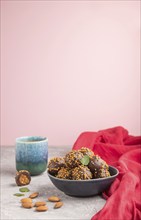 Chocolate caramel ball candies with almonds and a cup of coffee on a gray and pink background and