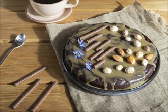 Homemade chocolate brownie cake with caramel cream and almonds with cup of coffee on wooden